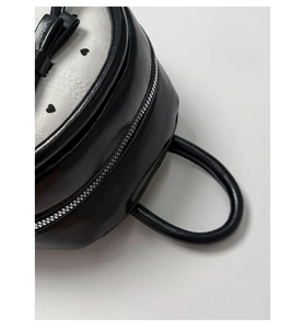 Detail of black leather backpack with white heart panel, bow, and silver zipper