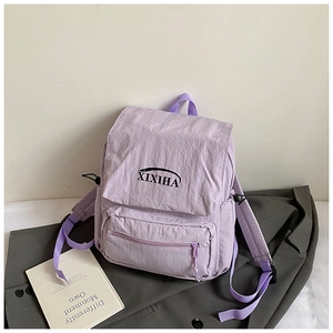 Detail view of lilac purple school backpack showing the flap opening and front zipper pocket