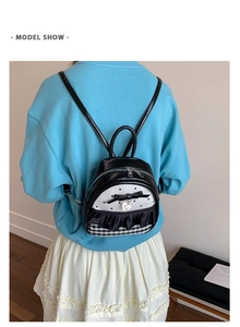 Detailed model show of a black and white mini backpack with heart pendant and bow