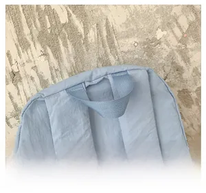 Gros plan sur la poignée renforcée et les coutures du sac à dos scolaire bleu clair