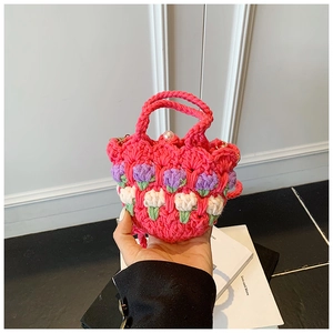 Close-up of handmade pink crochet bag with 3D purple floral patterns and pearl button