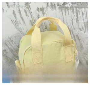 Detail of yellow nylon kids bag showing white plastic buckles and reinforced strap