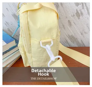 Detail of pale yellow nylon kids bag showing the detachable white hook and zipper