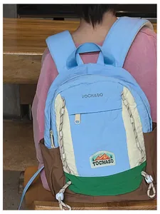 Vue arrière du sac à dos bleu clair bicolore montrant les bretelles et le cordon tressé