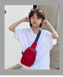Close-up of red nylon kids chest bag with blue strap and decorative lettering