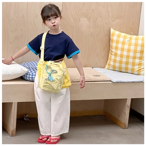 Yellow canvas crossbody bag for kids with puzzle charm and brand logo detail