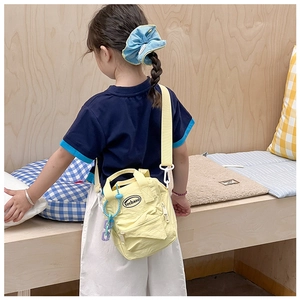Detail of yellow nylon mini crossbody bag for kids with adjustable strap and logo