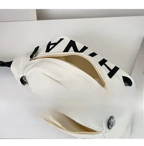 Dettaglio del materiale in tela e delle tasche con cerniera di questo borsello beige