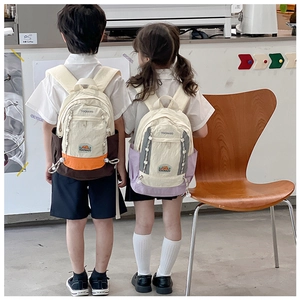 Détail de deux sacs à dos pour enfants au design color-block avec broderie TOCHASO