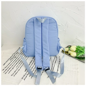 Detail view of the padded shoulder straps and back of the light blue nylon school backpack
