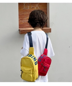 Rear view of children's canvas crossbody bags in yellow and red with adjustable straps