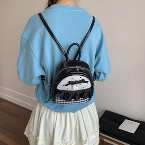 Detail of a mini leather backpack featuring polka dots, ruffles, and a heart charm
