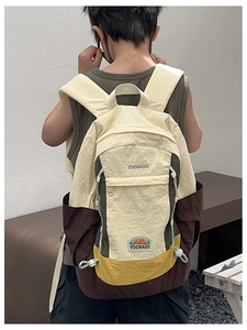 Vue arrière d'un enfant portant un sac à dos en nylon multicolore avec cordon de serrage