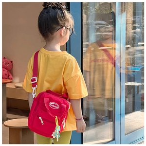 Detailed view of a red kids crossbody bag with colorful chain and brand logo