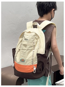 Détail d'un sac à dos enfant tricolore avec bretelles orange et écusson de montagne