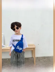 Dettaglio della borsa a tracolla blu in tela per bambini con scritta bianca e cinghia