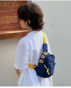 Detail of dark blue kids crossbody bag with yellow strap and side lettering