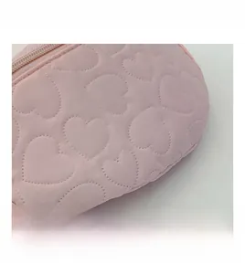 Gros plan sur la texture du tissu rose avec surpiqûres en cœur et détails de zip
