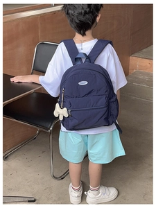 Detail of a dark blue nylon kids backpack with a cute animal charm and side mesh pocket