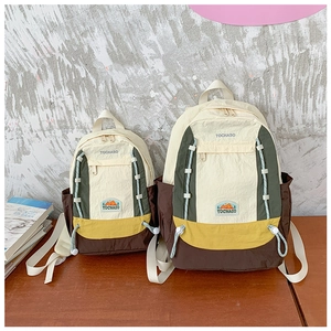 Comparaison de taille entre petits et grands sacs à dos en nylon bicolore sur bois