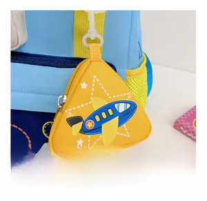 Detail showing a yellow triangle airplane coin purse attached to a backpack side