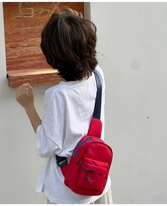 Detail of red canvas kids chest bag with DOUG print and adjustable blue strap