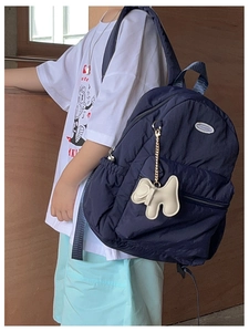 Detail of navy blue kids backpack with plush dog charm and side pocket on wooden background