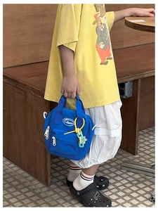 Blue kids nylon crossbody bag with zipper pocket and yellow chain detail in daily use