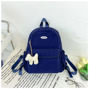 Detail view of navy blue kids backpack with quilted texture and a cute puppy keychain