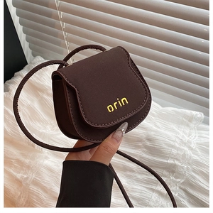 Detail of dark brown mini saddle bag with yellow orin logo print and matte texture