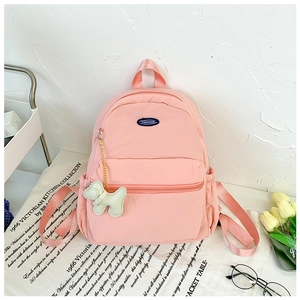 Detailed view of pink school backpack with a white balloon dog charm and front pocket