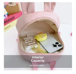Detail of pink rabbit backpack interior showing capacity for phone and accessories