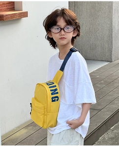 Detail of bright yellow kids crossbody bag with blue DOING text and adjustable strap