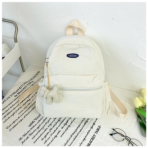 Close-up of off-white nylon school backpack with brand logo and cute plush doll pendant