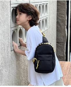 Outdoor close-up of a compact black and yellow kids sports crossbody bag for travel