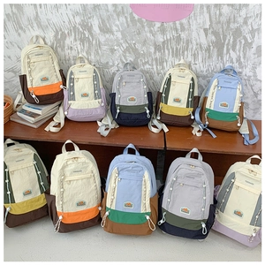 Vue détaillée de sacs à dos en nylon multicolores pour enfants avec zips et poches latérales