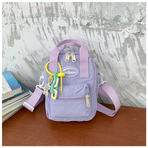 Detail view of mini lavender crossbody bag with yellow zipper and colorful chain