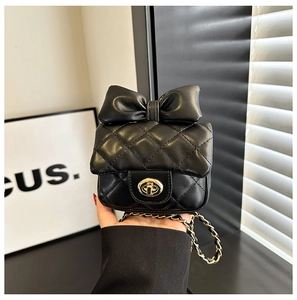 Mini sac matelassé noir avec nœud décoratif et fermoir rotatif doré en main