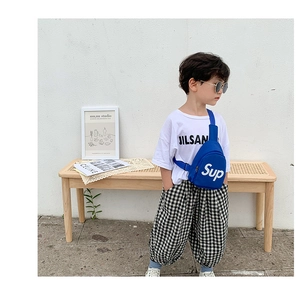 Dettaglio del borsello blu da bambino con scritte bianche e abbigliamento streetwear trendy