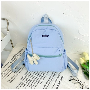 Detail of light blue nylon backpack with puppy charm and front zipper compartment