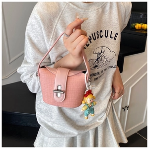 Close-up of pink tweed mini bucket bag with leather handle and cute doll pendant detail