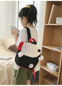 Rückansicht eines Mädchens mit einem süßen schwarz-weißen Welpen-Rucksack mit roten Trägern