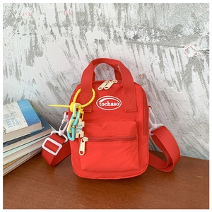 Detail of red nylon kids cross-body bag with colorful chain and puzzle piece keychain