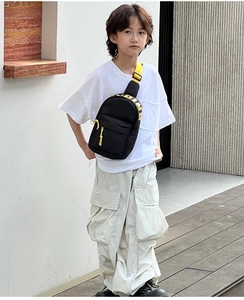 Detail of black nylon kids chest bag with adjustable bright yellow letter print strap
