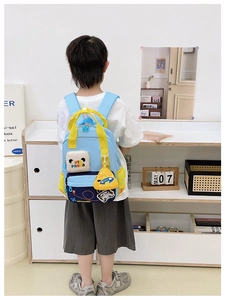 Blue kids school bag with cute panda patch and yellow plane accessory on child