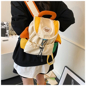 Detail of color-block canvas backpack featuring cloud-shaped patch and drawstring closure