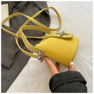 Detail of a bright yellow crossbody bag with woven texture and silver twist lock