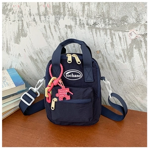 Detail of navy nylon kids backpack with yellow zipper and puzzle charm on a wooden table
