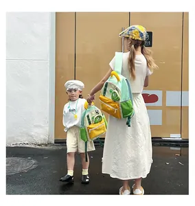 Outdoor shot of mother and child wearing matching green and yellow dinosaur backpacks