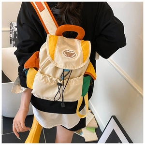 Detail view of colorful dopamine backpack with orange top handle and drawstring closure
